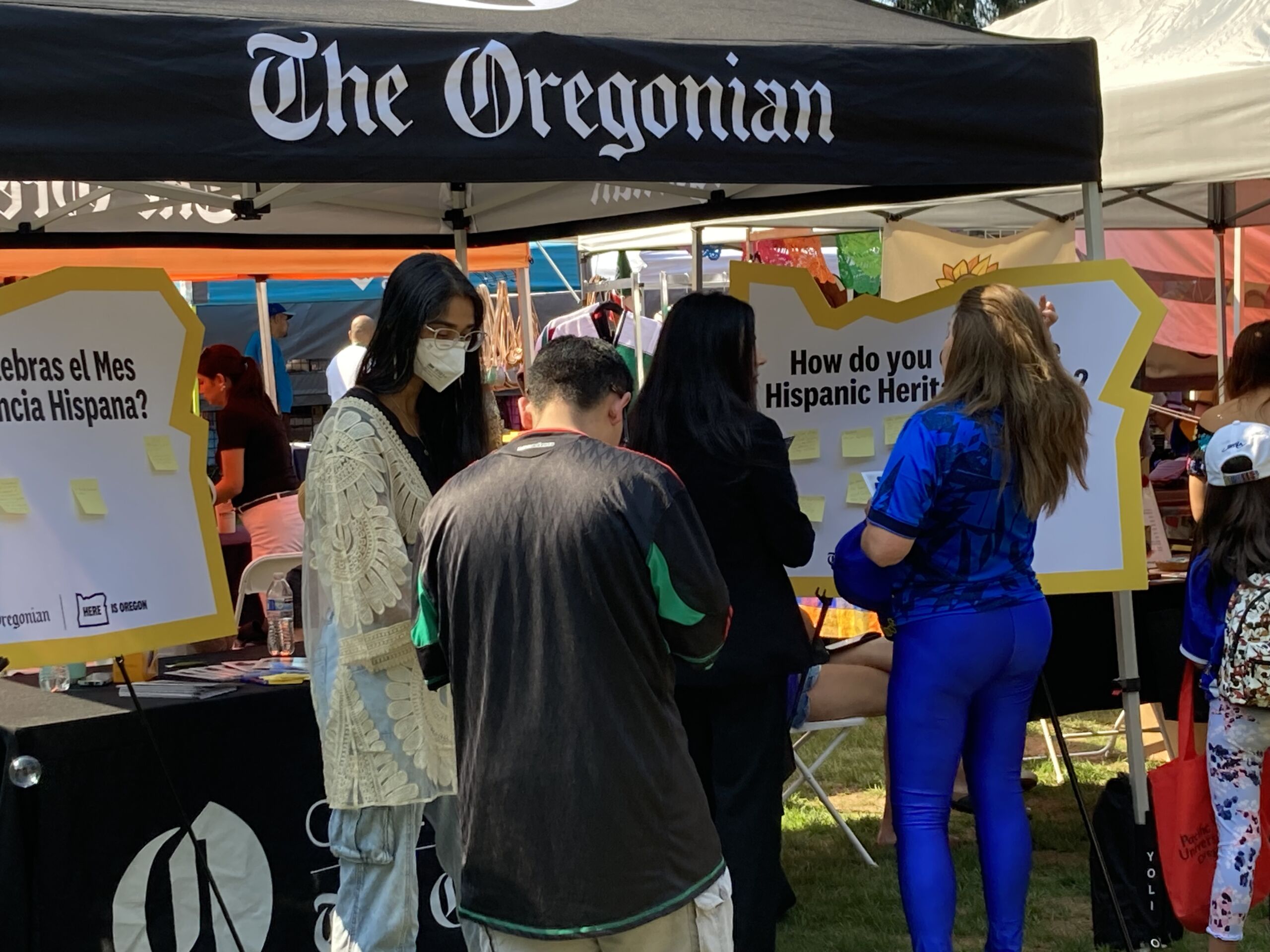 A group of people under a tent with The Oregonian logo